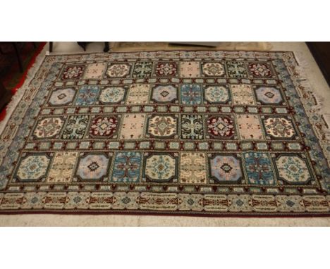 A Persian style rug, the central panel set with tiled decoration on a aubergine ground within a stepped aubergine, blue and c