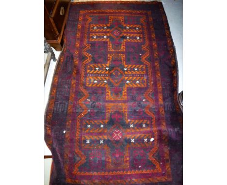 A Belouch rug the central panel set with three cross shaped medallions on a dark plum and black ground within a stepped plum,