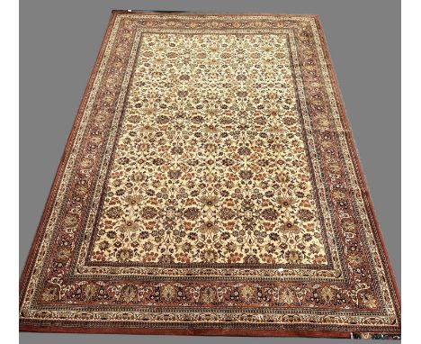 Machine-made Persian style carpet, the sand coloured field with all over foliate design, enclosed with similar borders, 350cm