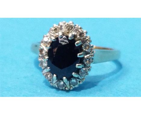 An oval sapphire, set in a surround of 12 diamonds on a 9ct gold shank