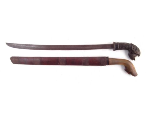 Two Malay /Indonisian Klewang swords, one with horn grip, the other with carved Dog horn grip and hardwood scabbard, (2) 70cm