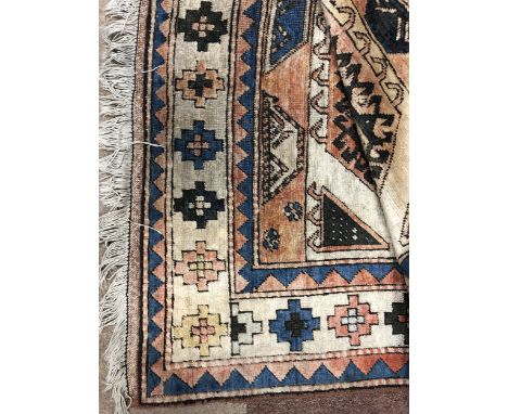 MIDDLE EASTERN FRINGED CARPET, in shades of red, blue, green and brown with symmetric shapes