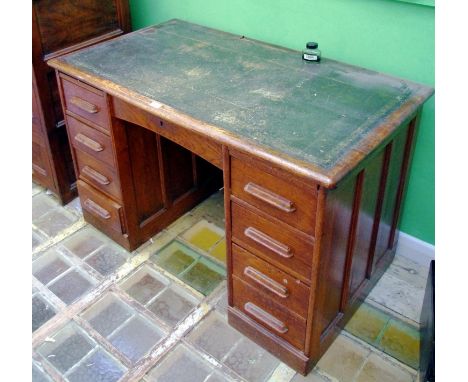 A 1930 oak pedestal desk, central arched door, four drawers to pedestals, leather writing surface, 76cm high ,122cm wide, 69c