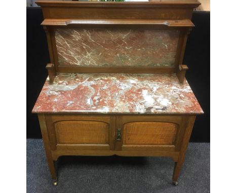 An Arts and Crafts oak washstand, rouge marble splash back and top, two fielded panel doors, tapering square legs, brass cast