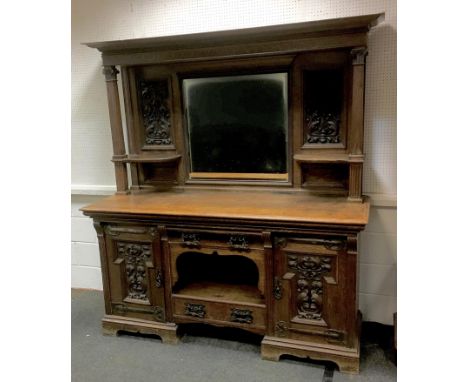 A Victorian Art Nouveau oak sideboard, carved back with central rectangular mirror, shaped side shelves, base drawers, open a