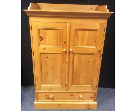 A modern pine gentleman?s low wardrobe, three quarter gallery to top, two panel doors over long drawer, plinth base. 154cm hi