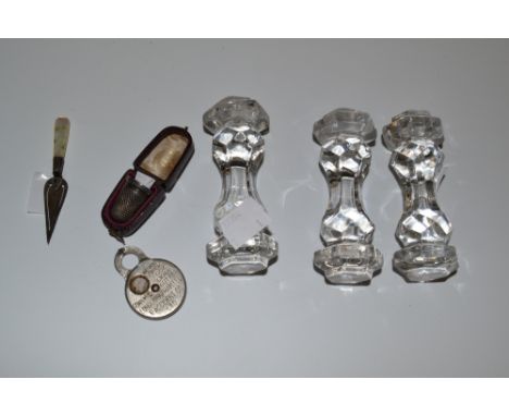 A set of three faceted glass knife rests; an Edwardian silver and mother of pearl book marker, fashioned as a trowel, Birming