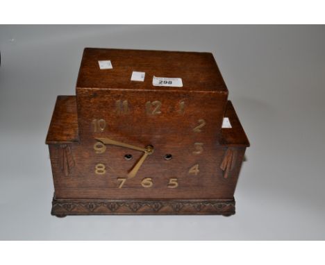 An Art Deco geometric oak mantel clock, the dial applied with bold Arabic numerals, the base carved with geometric motifs, st