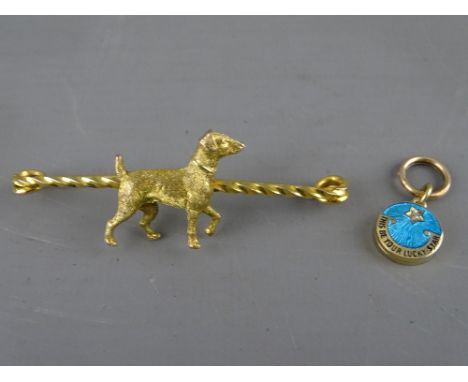 A nine carat gold terrier dog bar brooch, 5.9 grms and a fifteen carat gold and enamel lucky star locket, 3.5 grm 7 cms long 