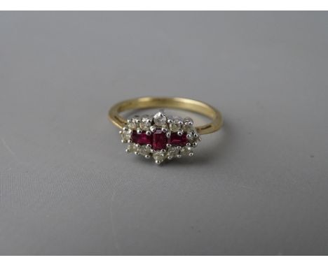 Nine carat gold ruby and diamond cluster dress ring, having three oblong cut centre rubies with surrounding round cut diamond