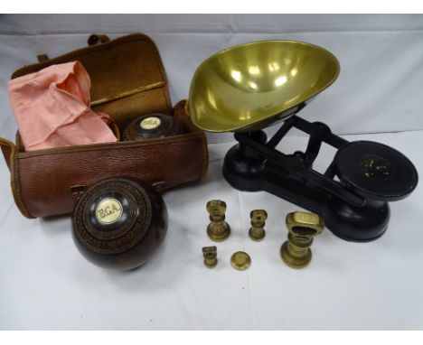 A pair of vintage wooden bowling balls with ivory button detail in carry case and a reproduction set of cast iron and brass k