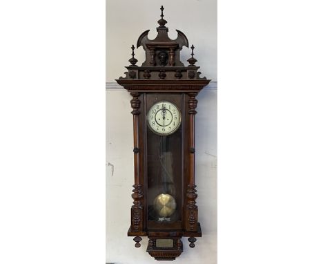 A late Victorian Vienna regulator type wall clock, with a carved cresting, circular dial and Arabic numerals