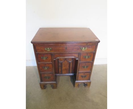 A Georgian mahogany kneehole desk with re-entrant cornered top over a slide and eight drawers with a central cupboard, on sha