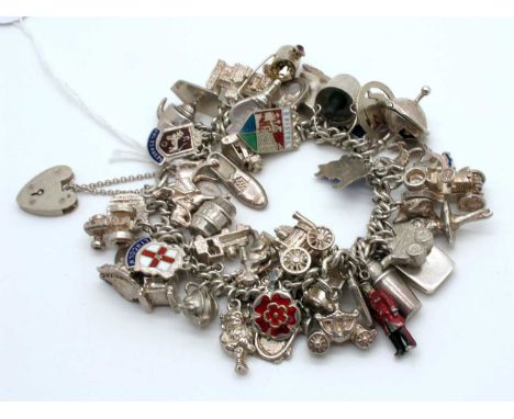 A Curb Link Charm Bracelet, suspending numerous assorted novelty charm pendants, including enamel shield souvenirs, etc.