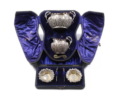 A cased silver sugar basin and cream jug with looped handles and embossed decoration, Birmingham 1897, together with a small 