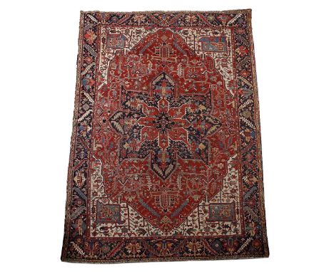 A Heriz red ground carpet  with central medallion and blue border, 344cm x 250cm approx.