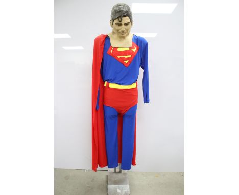 Superman dress up outfit with Christopher Reeve silicone mask with painted features, displayed on stand