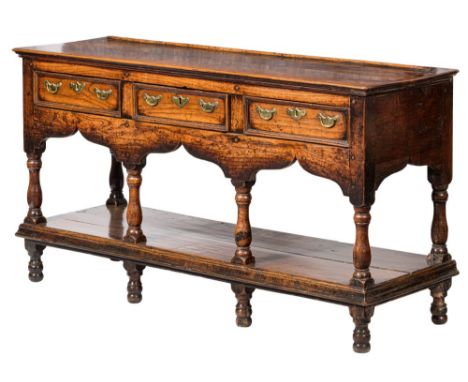 An early 18th Century oak rectangular dresser base:, of small size with a ledge back, fitted with three short moulded panel d