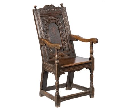 A James I carved oak open armchair:, the raked back with guilloche flowerhead top rail with scroll cresting and bun finials, 