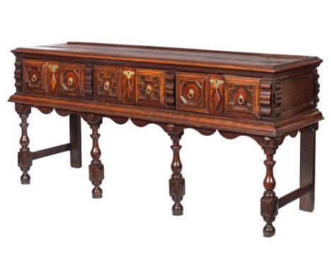 A 17th Century oak rectangular dresser base:, the top with a ledge back and moulded edge, containing three short geometricall