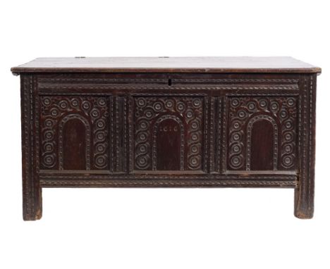 An early 17th Century carved oak rectangular coffer: with a plain hinged moulded top, the front with gouged frieze and stiles