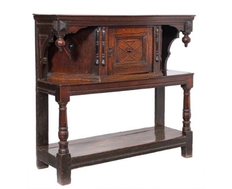A 17th Century oak livery cupboard:, the top with a moulded pendant hung frieze, the central canted cupboard enclosed by a mo