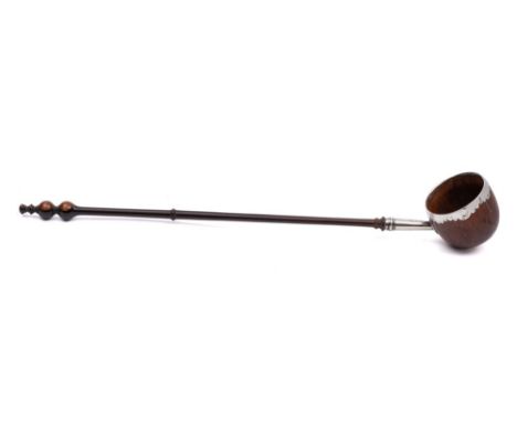 An 18th Century toddy ladle:, the coquilla nut bowl with silver rim and mount to lignum vitae turned handle, 33cm long.