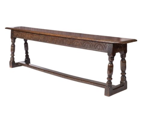 A 17th Century oak West Country bench: the top with moulded edge, the frieze and ends with lunette foliate ornament on turned