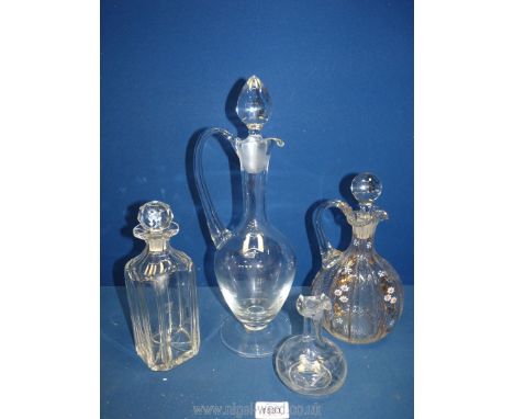 Three various decanters to include one with painted flowers and leaves, a large footed decanter, and vinegar bottle