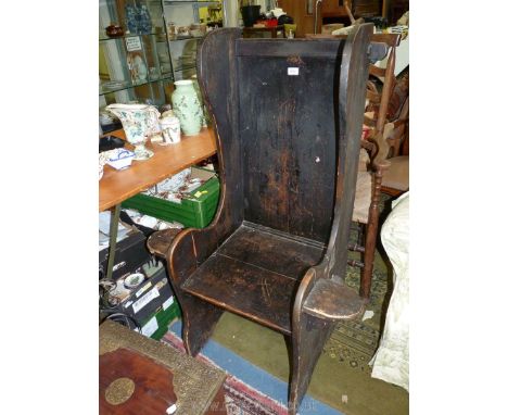 A very rustic dark stained peg joyned lambing style Armchair having a small shelf incorporated to either arm with label 'Crwy