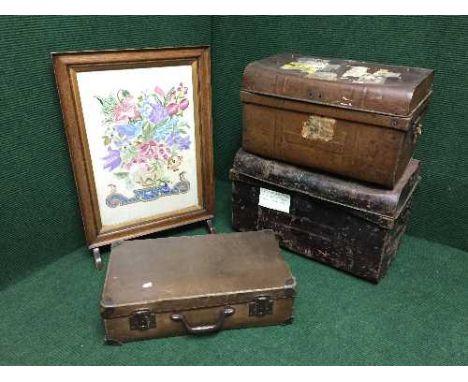 An oak framed embroidered fire screen, vintage luggage case and two tin trunks