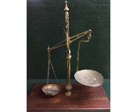 A set of antique brass balance scales mounted on mahogany plinth
