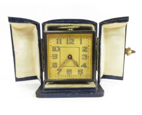 A 20th century travelling clock with a gold dial and an associated blue leather case