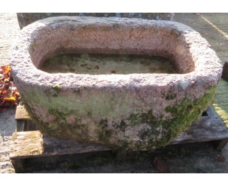 A pink granite water trough of rectangular form with rounded end, 39cm high 77cm wide x 51.5cm