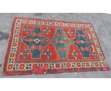 A Middle Eastern wool carpet the central field with three shaped medallions within stylised floral borders and with two scrip