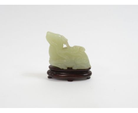 A Chinese jade carving of dragon, seated on a fitted wooden base, 5.8cm long, 3.7cm high