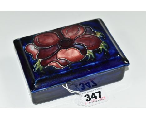 A MOORCROFT POTTERY RECTANGULAR LIDDED TRINKET BOX, 'Anemone' pattern on a dark blue ground, paper Queen Mary sticker to base
