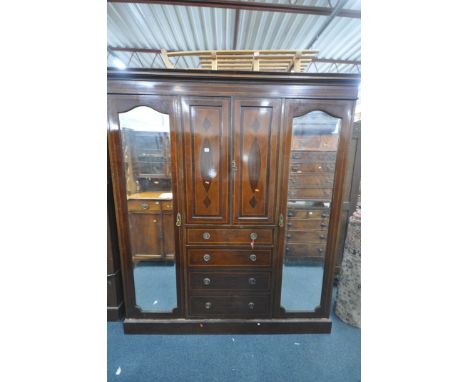 AN EDWARDIAN MAHOGANY COMPACTUM WARDROBE, with two mirrored doors, flanking two cupboard doors, above four drawers, width 190