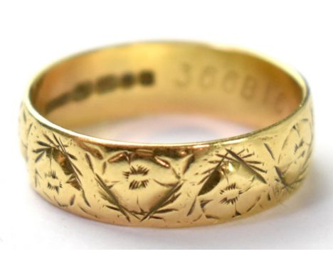 An 18ct gold band ring with a repeating flower head pattern, size Q, approx 3.8g.