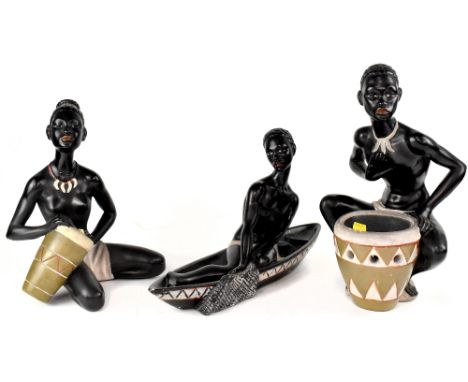 Three early 20th century painted plaster figures depicting African ladies and boy with drum, cook pot and fishing boat, heigh