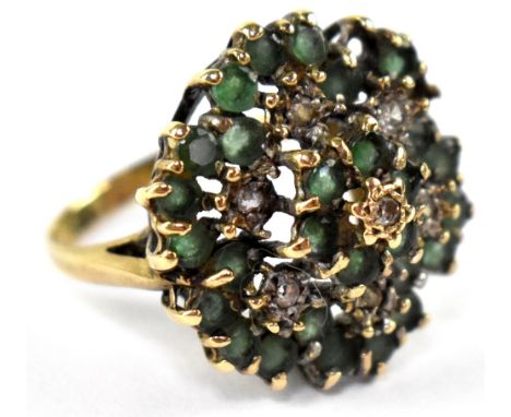 A 9ct gold ring in the form of a flower head set with seven white stones in a surround of green stones (two stones missing), 