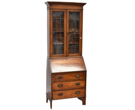 An early 20th century oak bureau bookcase with pair of leaded glazed doors enclosing three adjustable shelves above fall fron