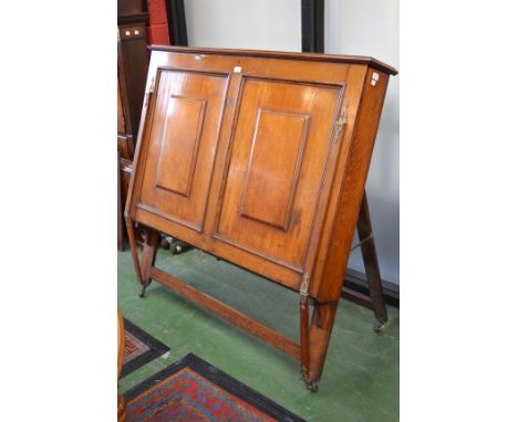 A Victorian country house easel-back folio cabinet, hinged top, fall front with a pair of raised and fielded panels enclosing