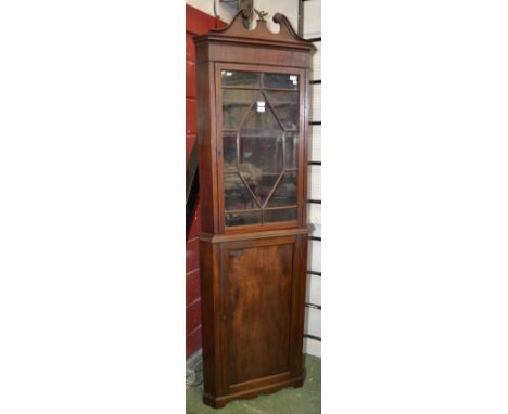 A 19th century mahogany floor standing corner cupboard, swan neck pediment with eagle finial above and astragal glazed door, 