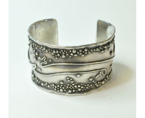A silver coloured metal cuff bangle, with stylised decoration, indistinctly signed, inscribed 1/1 and dated 1981   Condition 