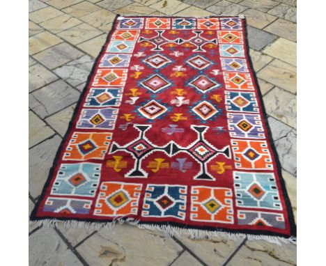 EXTRA LOT:  A kelim, with stylised geometric motifs on a red ground, 310 x 165 cm, an Elizabeth Kitson limited edition print,