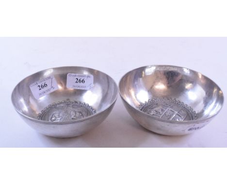 A silver coloured metal bowl, embossed a two headed eagle, 12 cm diameter, and another similar, embossed a coat of arms (2)