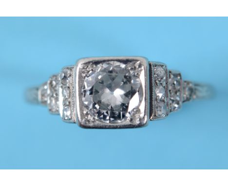 An Art Deco platinum and diamond ring, the central diamond in diamond set shoulders, approx. ring size K½  See inside back co