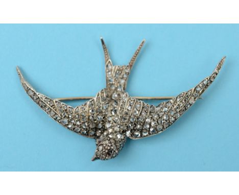 A diamond brooch, in the form of a swallow, with ruby cabochon eyes  See front cover colour illustration   Condition report  
