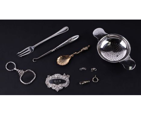 A George V silver tea strainer, Birmingham 1922, 40g; together with other items of silver to include a Gin bottle label, Lond
